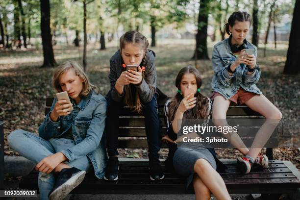 teenagers in the public park using smartphones - boys mobile phone group stock pictures, royalty-free photos & images