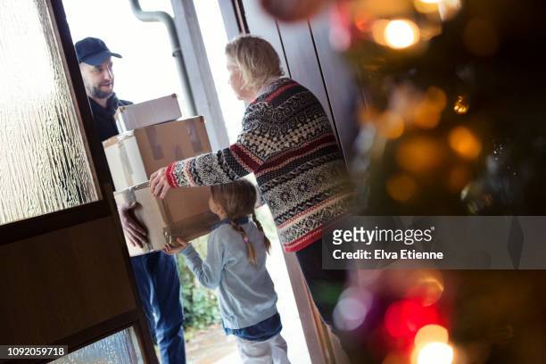 senior woman and child receiving christmas packages delivered by postman - child delivering stock-fotos und bilder