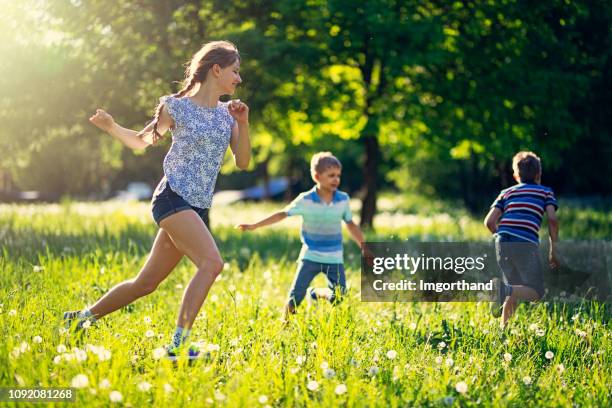 kids running in meadow will of dandelions - playing tag stock pictures, royalty-free photos & images