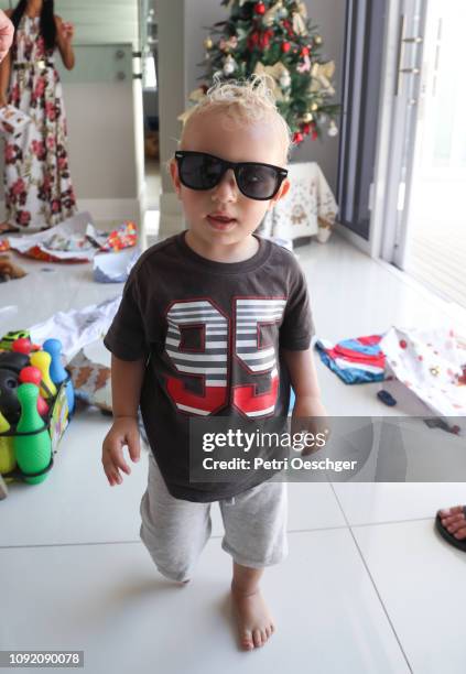 a toddler unwrapping presents on christmas. - baby in sunglass stock-fotos und bilder