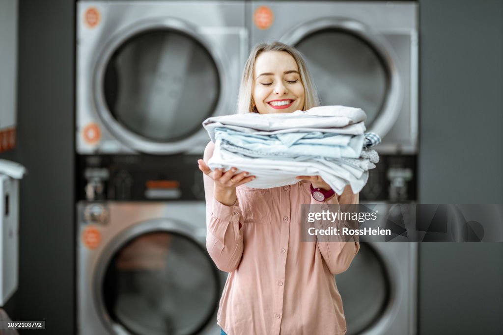 Woman with ironed clothes in the laundry