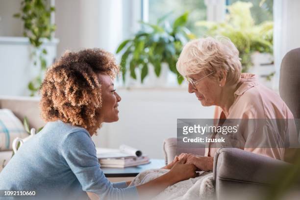 cheerful home caregiver consoling senior woman - volunteer aged care stock pictures, royalty-free photos & images
