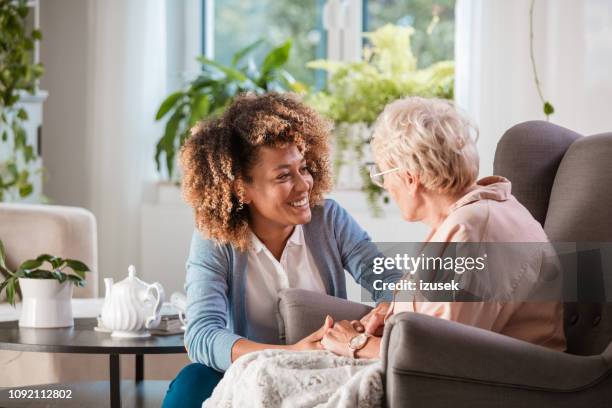 sympathique infirmière soutenant une dame agée - profession médico sociale photos et images de collection