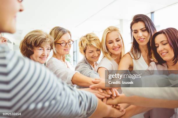frauen machen einen haufen von händen - miteinander verbunden stock-fotos und bilder
