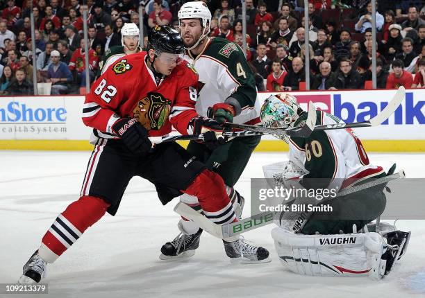 Tomas Kopecky of the Chicago Blackhawks watches as goalie Jose Theodore of the Minnesota Wild stops the puck and Clayton Stoner of the Wild skates in...