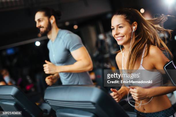 sporty people running on treadmills in a health club - health club stock pictures, royalty-free photos & images