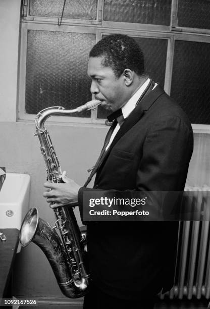 American jazz saxophononist, composer and musician John Coltrane pictured warming up in a dressing room backstage prior to performing at the Gaumont...
