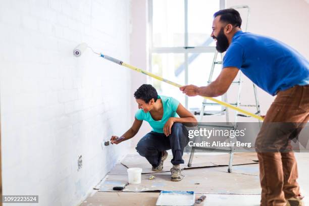 young mixed race couple painting their home - painter in overhauls bildbanksfoton och bilder