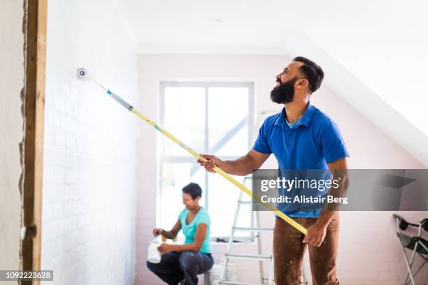 young mixed race couple painting their home - protective sheet stock pictures, royalty-free photos & images