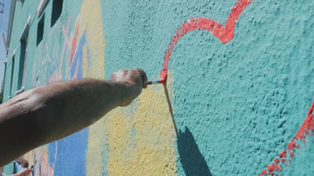 Man drawing heart on sunny wall mural
