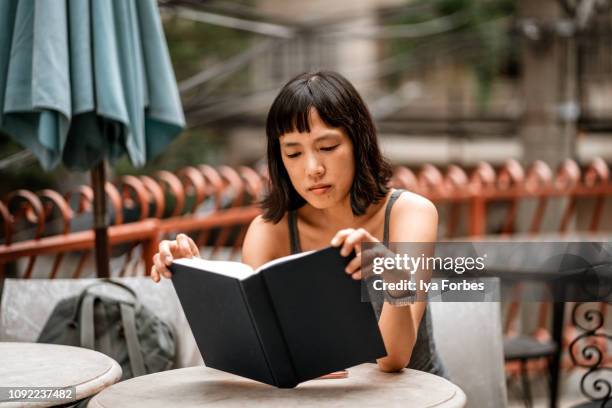 filipino woman reading book - reading outside stock pictures, royalty-free photos & images