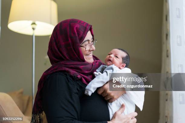 großmutter holding neugeborenes baby boy - happy muslim stock-fotos und bilder