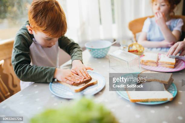 maken van broodjes voor de lunch - boy packlunch stockfoto's en -beelden