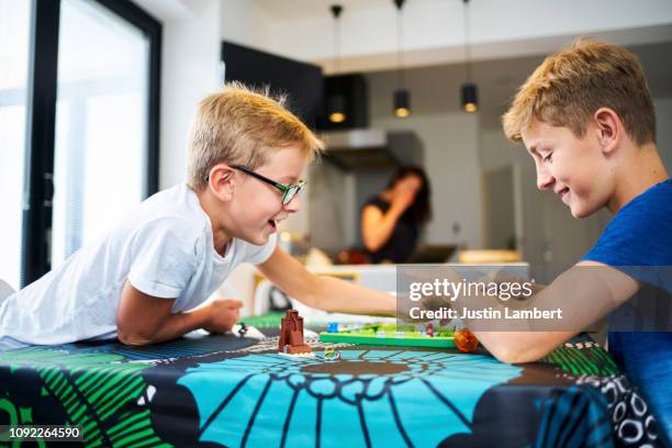 two brothers laughing playing a board game on the kitchen table - boardgame stockfoto's en -beelden