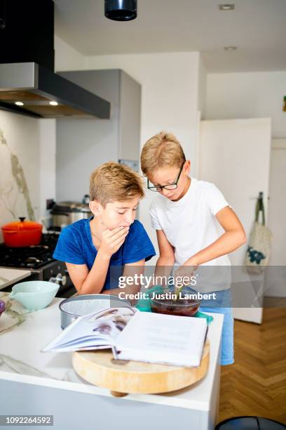 two boys cooking together at home baking a chocolate cake - saltdean stock pictures, royalty-free photos & images