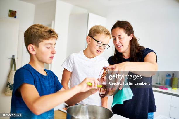 family cooking together at home baking a chocolate cake all getting involved in the process - saltdean stock pictures, royalty-free photos & images