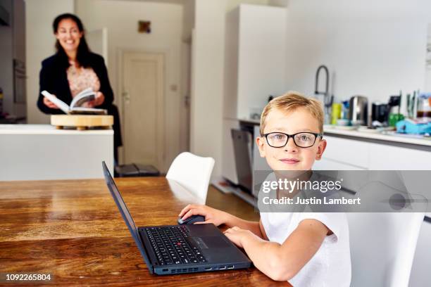 child looking up from his laptop sitting at the kitchen table - saltdean stock pictures, royalty-free photos & images