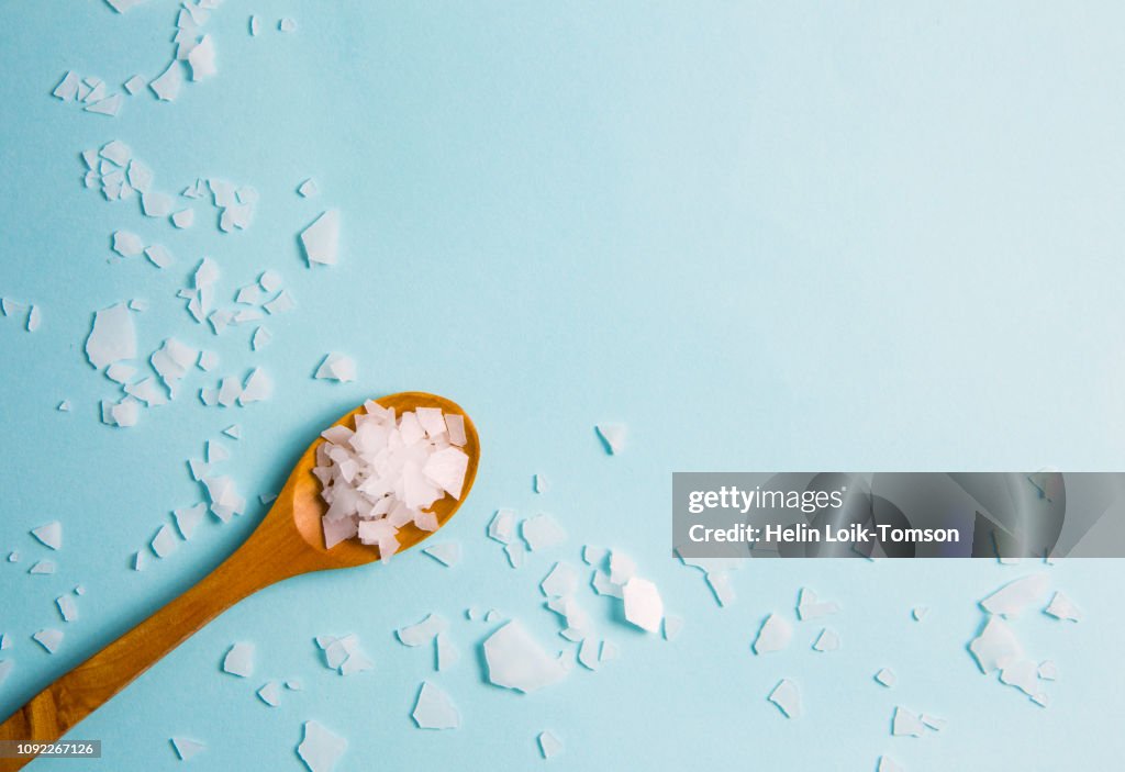 Magnesium vitamin flakes on wooden spoon.