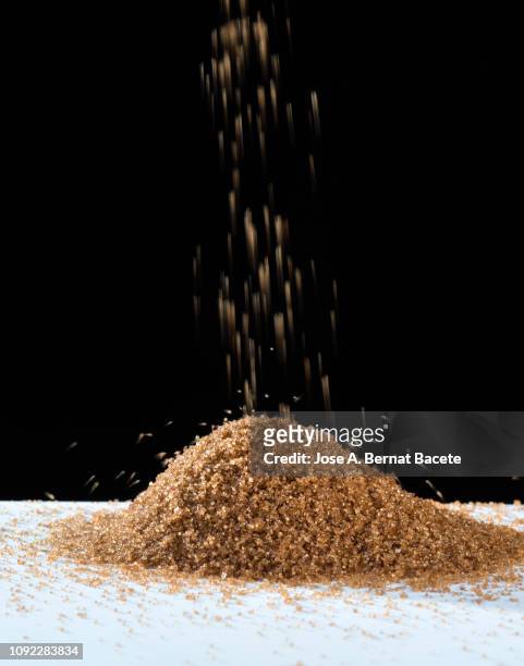 organic sugar mound  brown on a black background. - sugar pile stock pictures, royalty-free photos & images