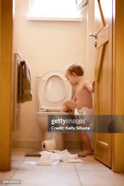 a mischievous toddler boy climbs into the toliet - childrens closet stockfoto's en -beelden