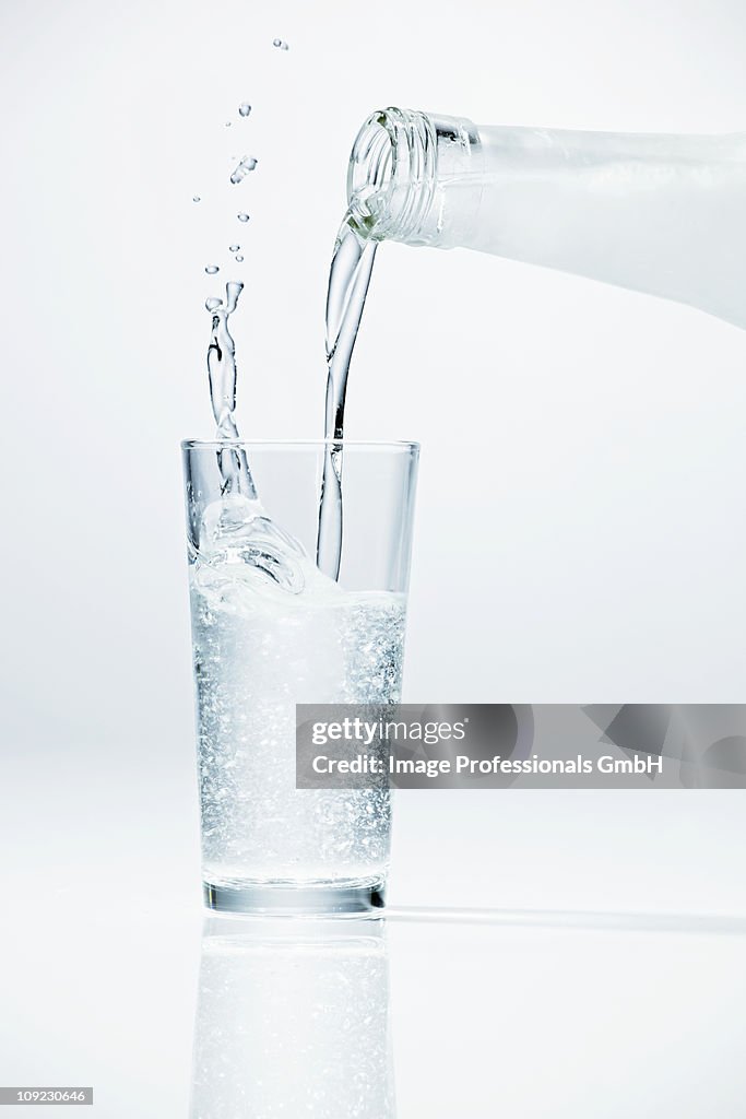 Pouring ouzo from bottle into glass, close-up