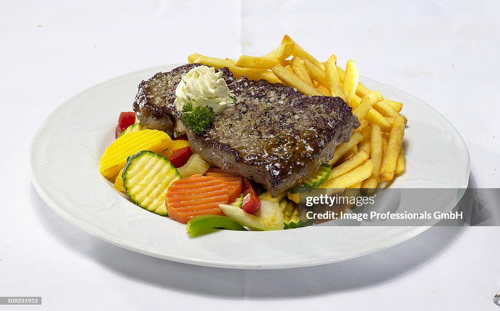 Rump steak with chips and vegetables on plate