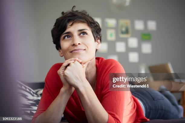 portrait of smiling woman lying on couch at home - inspirieren stock-fotos und bilder