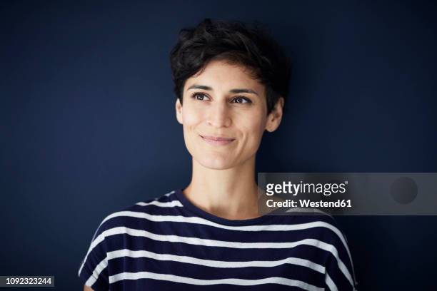 portrait of smiling woman at blue wall - short stockfoto's en -beelden