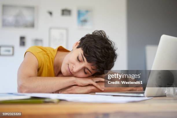 woman at home resting on table with laptop - taking a nap stock-fotos und bilder