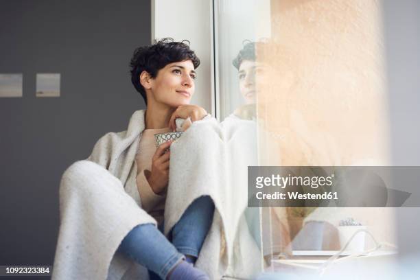 relaxed woman at home sitting at the window - calor fotografías e imágenes de stock