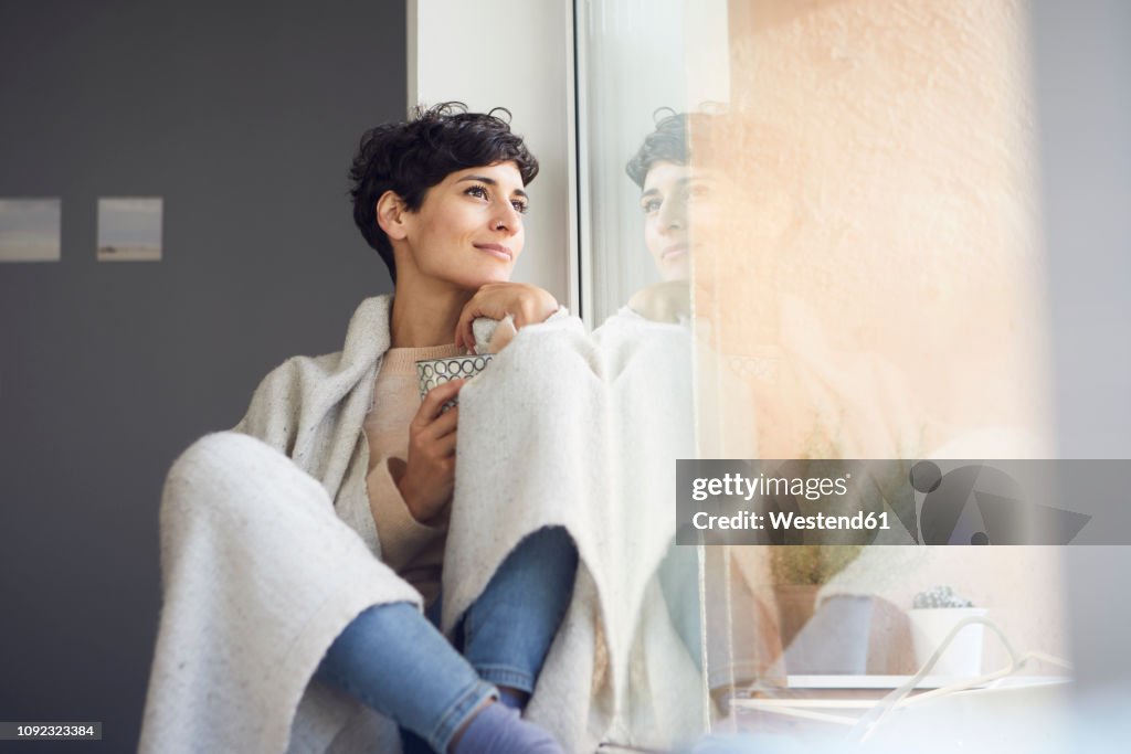 Relaxed woman at home sitting at the window