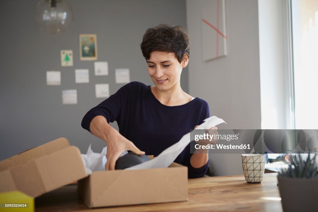 Smiling woman packing parcel at home