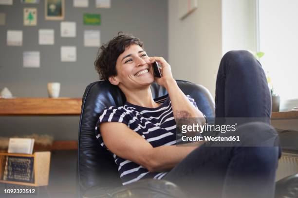 happy woman talking on cell phone at home - smartphone zuhause stock-fotos und bilder