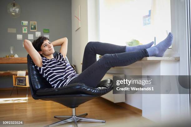 smiling woman sitting at home relaxing - hands behind head stock pictures, royalty-free photos & images