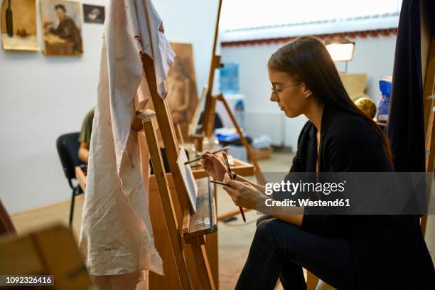 student painting on easel in art class - art class stockfoto's en -beelden