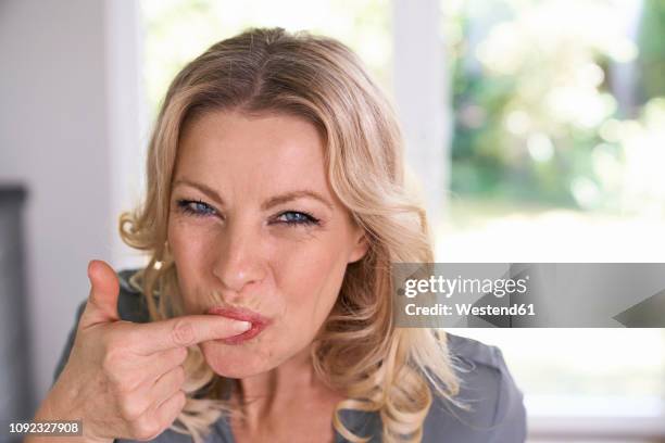 portrait of smiling woman tasting food from her finger - women licking women stock pictures, royalty-free photos & images