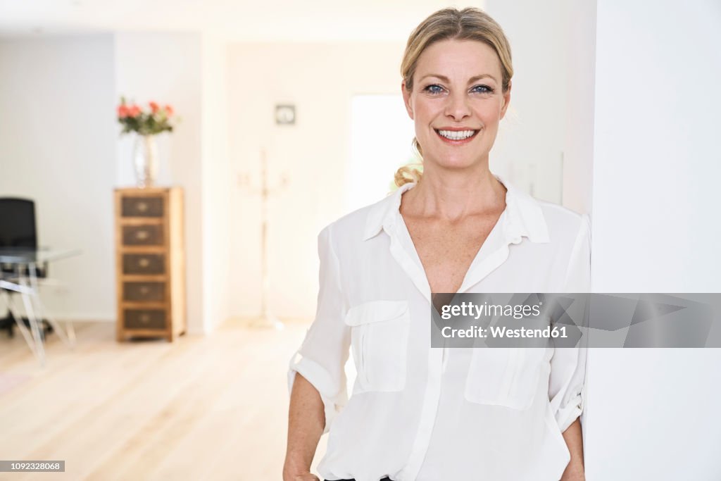 Portrait of smiling woman wearing white blouse at home