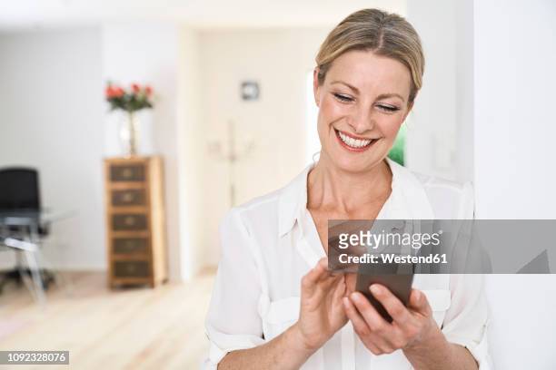 smiling woman using cell phone at home - omlaag kijken stockfoto's en -beelden