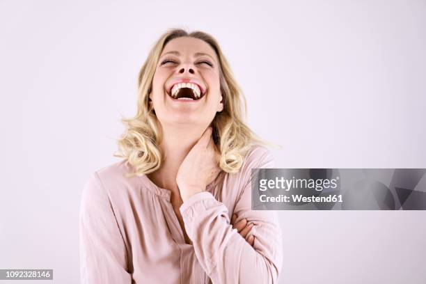 portrait of laughing blond woman leaning back - lachen stock-fotos und bilder