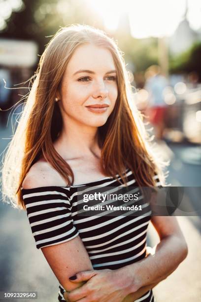 portrait of smiling young woman wearing striped dress at sunset - striped dress ストックフォトと画像