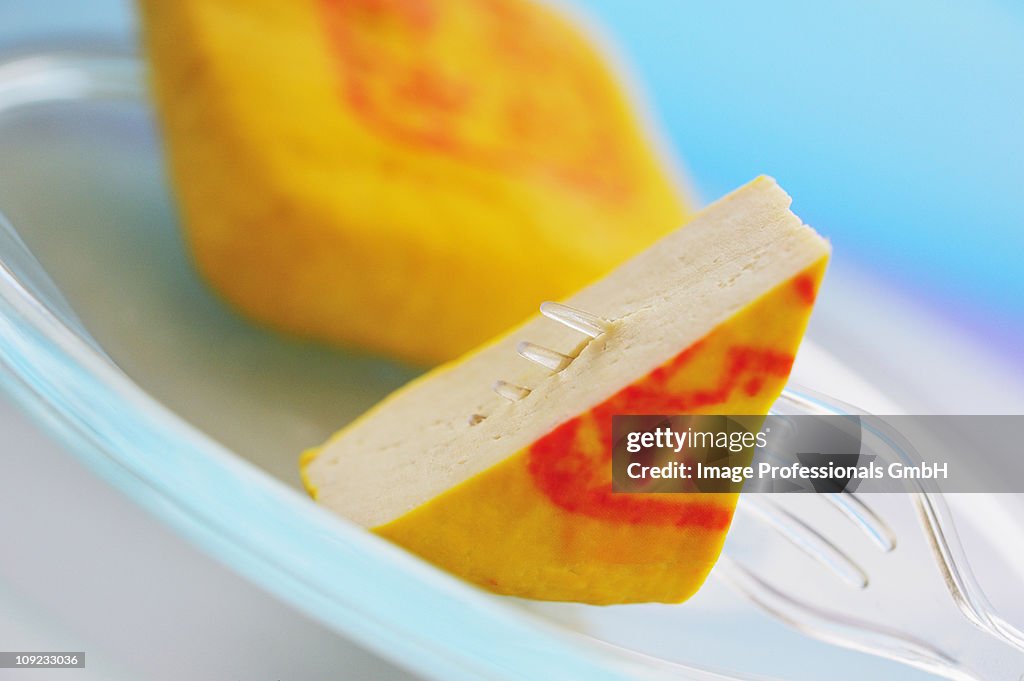 Slices of tofu with fork on plate, close-up