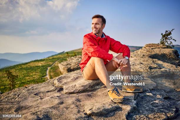 man sitting on rock enjoying the view during hiking trip - outdoor guy sitting on a rock stock pictures, royalty-free photos & images