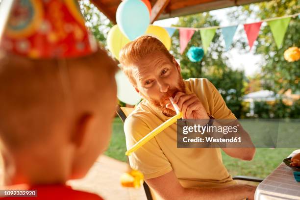 playful father with son on a garden birthday party - birthday streamers stock-fotos und bilder