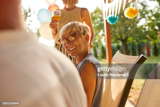 smiling mature woman looking at husband on a garden party - retirement invitation stock pictures, royalty-free photos & images