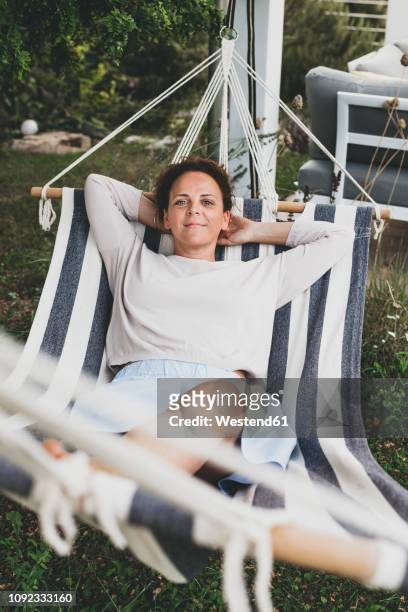 portrait of smiling woman lying in a hammock - person escaping stock pictures, royalty-free photos & images