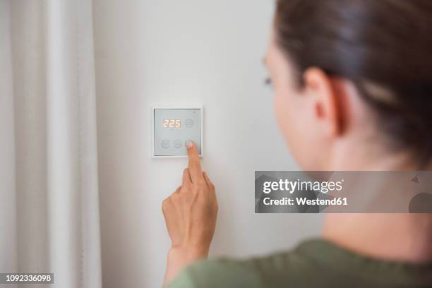 woman using smart home switch on wall - handy in der hand foto e immagini stock