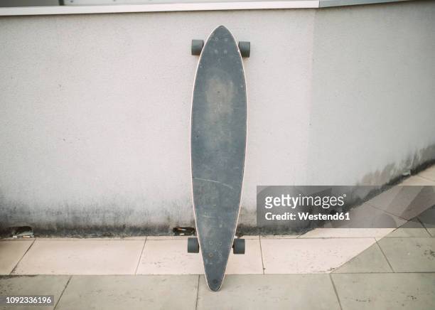 longboard in the street leaning against a wall - surfar com prancha longa imagens e fotografias de stock