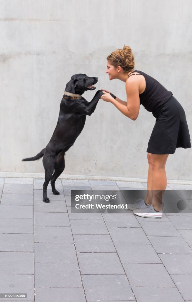 Young woman dressed in black with her black dog