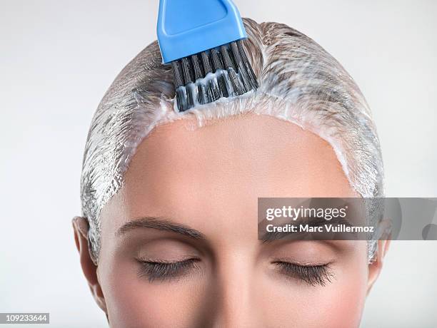 young woman applying hair color - hair color foto e immagini stock