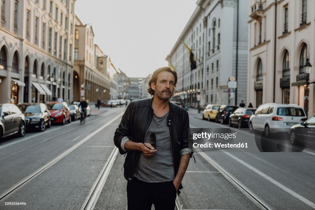 Man wearing leather jacket walking in the street, Munich, Germany